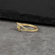 Side view of a 10k gold mini Uzi gun ring on gray stone.