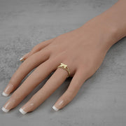 Model hand wearing a 10k gold mini Uzi gun ring on gray background.