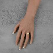 Mannequin hand with French tip nails wearing a 10k gold Uzi ring on gray background.