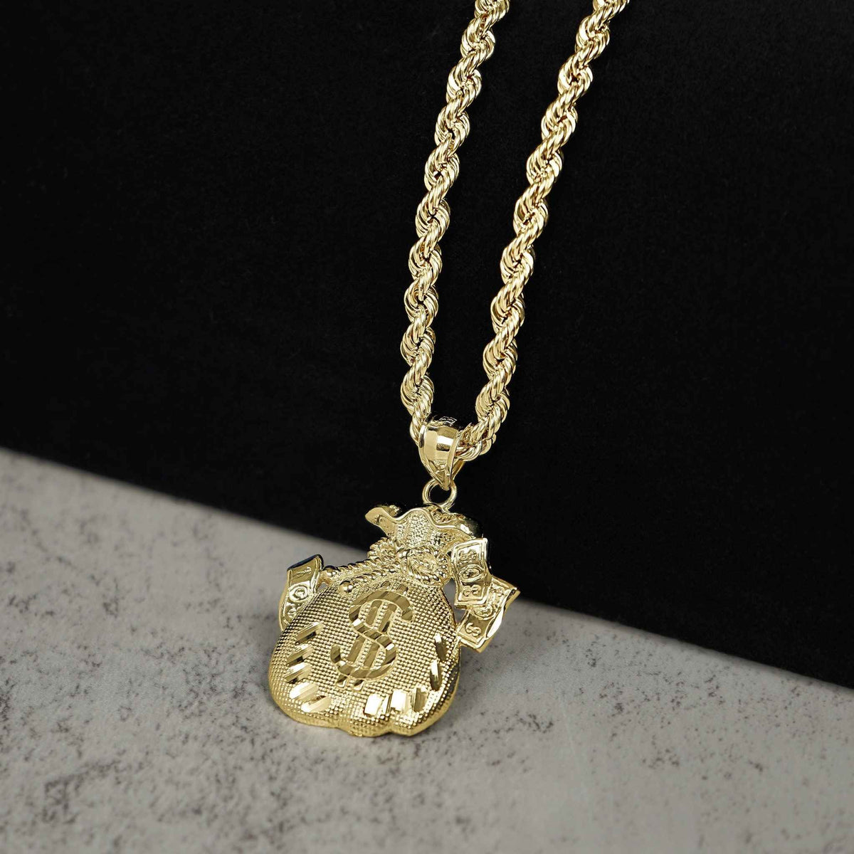 10k gold money loot bag pendant necklace with rope chain on dark background.