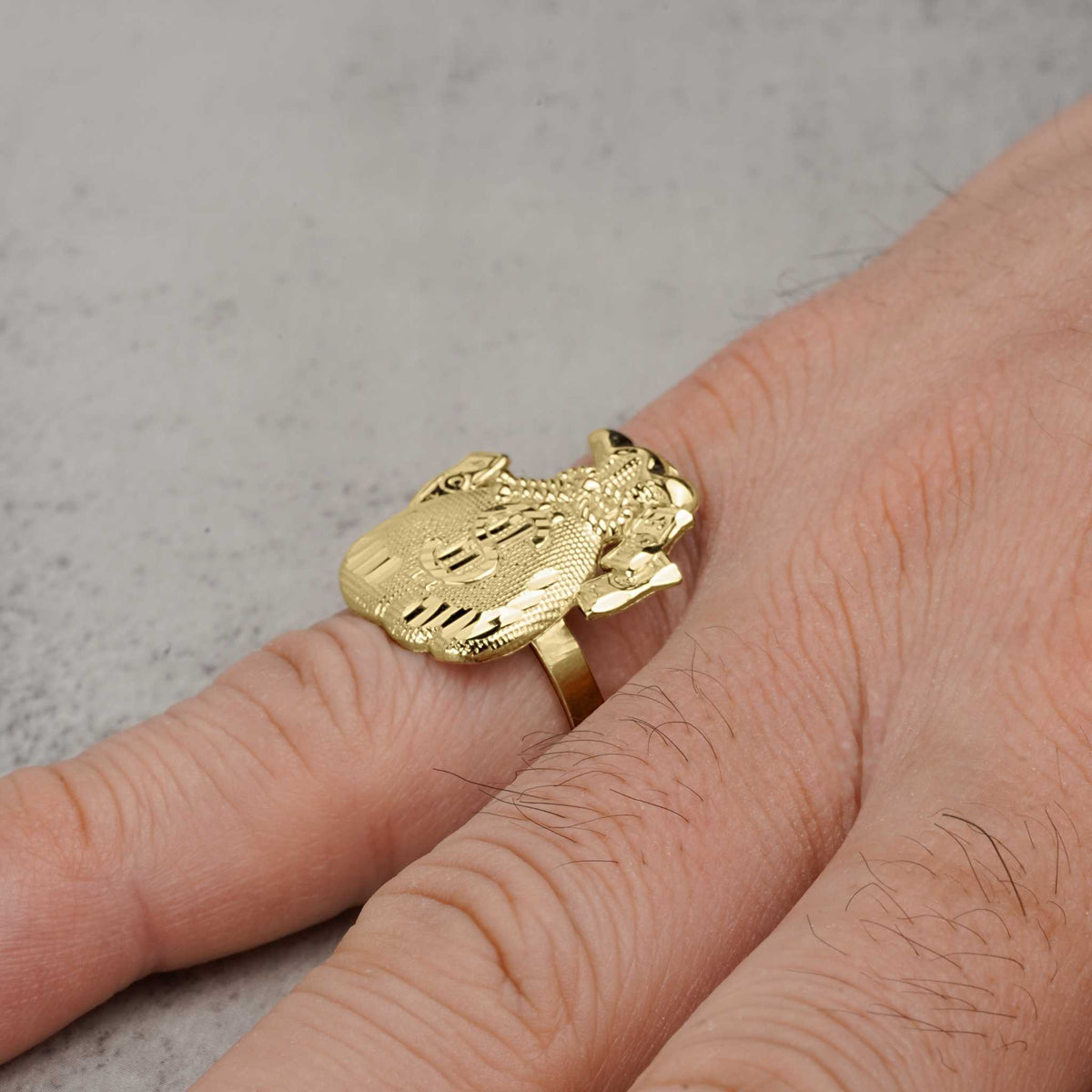 A 10k gold money loot bag signet ring being worn on a person's finger.
