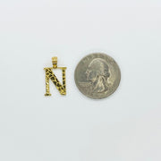 Size comparison of 10k gold nugget initial N pendant beside a US quarter coin.