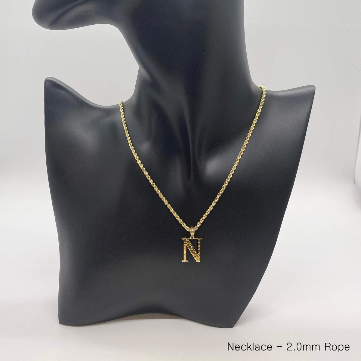10k yellow gold nugget initial N pendant necklace on rope chain on black display bust.