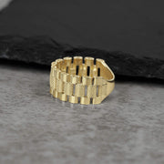 10k gold presidential-style Rollie pattern band ring on a grey stone background.