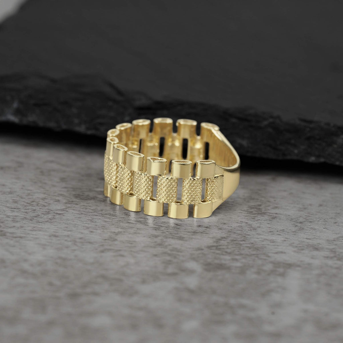 10k gold presidential-style Rollie pattern band ring on a grey stone background.