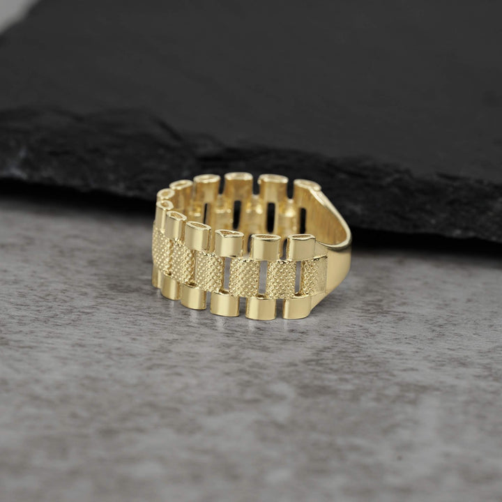 10k gold presidential-style Rollie pattern band ring on a grey stone background.