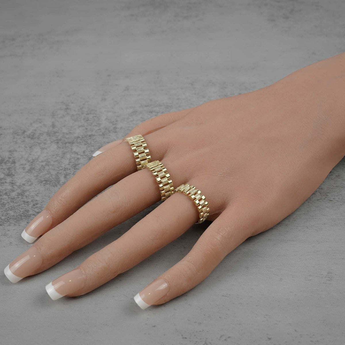 Hand model wearing two 10k gold watch-style link rings arranged horizontally.