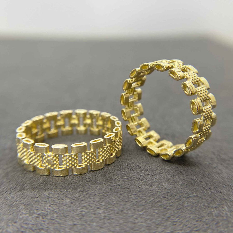 Two 10k gold Pattern Rollie Eternity Band rings with textured design on a gray surface