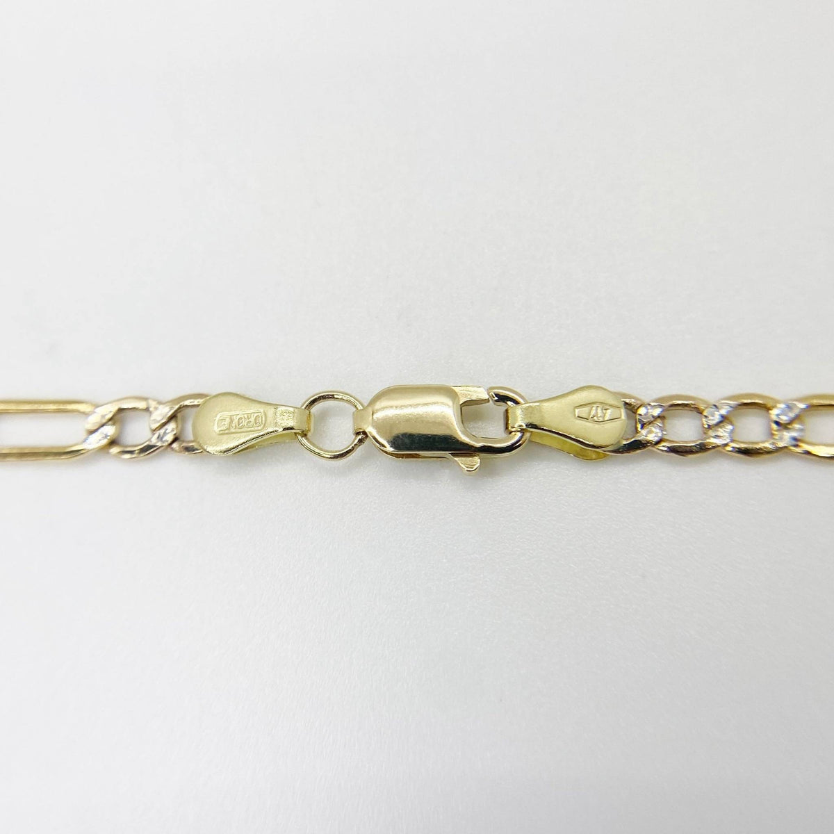 Close-up of 10k yellow gold Figaro chain showing lobster clasp on white background.