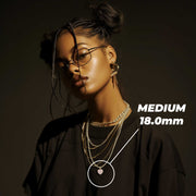 Model wearing eyeglasses and layered necklaces featuring the medium 18.0mm gold and pink heart pendant.
