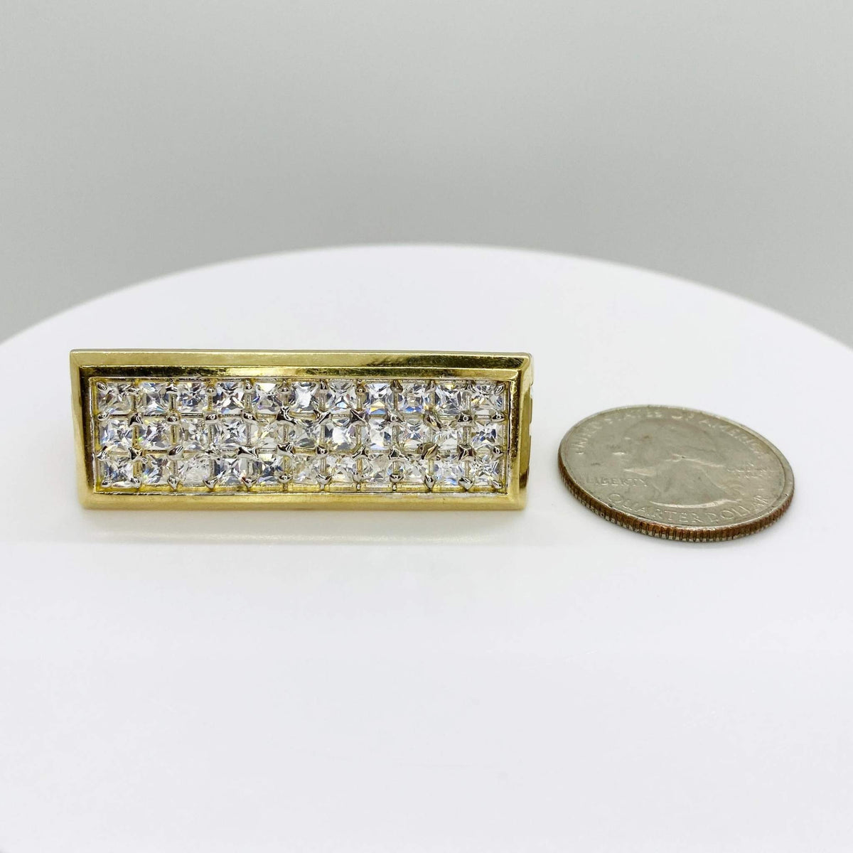 10k Gold Princess rectangular ring with Cubic Zirconia next to a quarter on a white surface