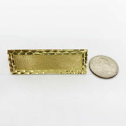 10k Gold rectangular three finger ring next to a silver dollar coin on a white background