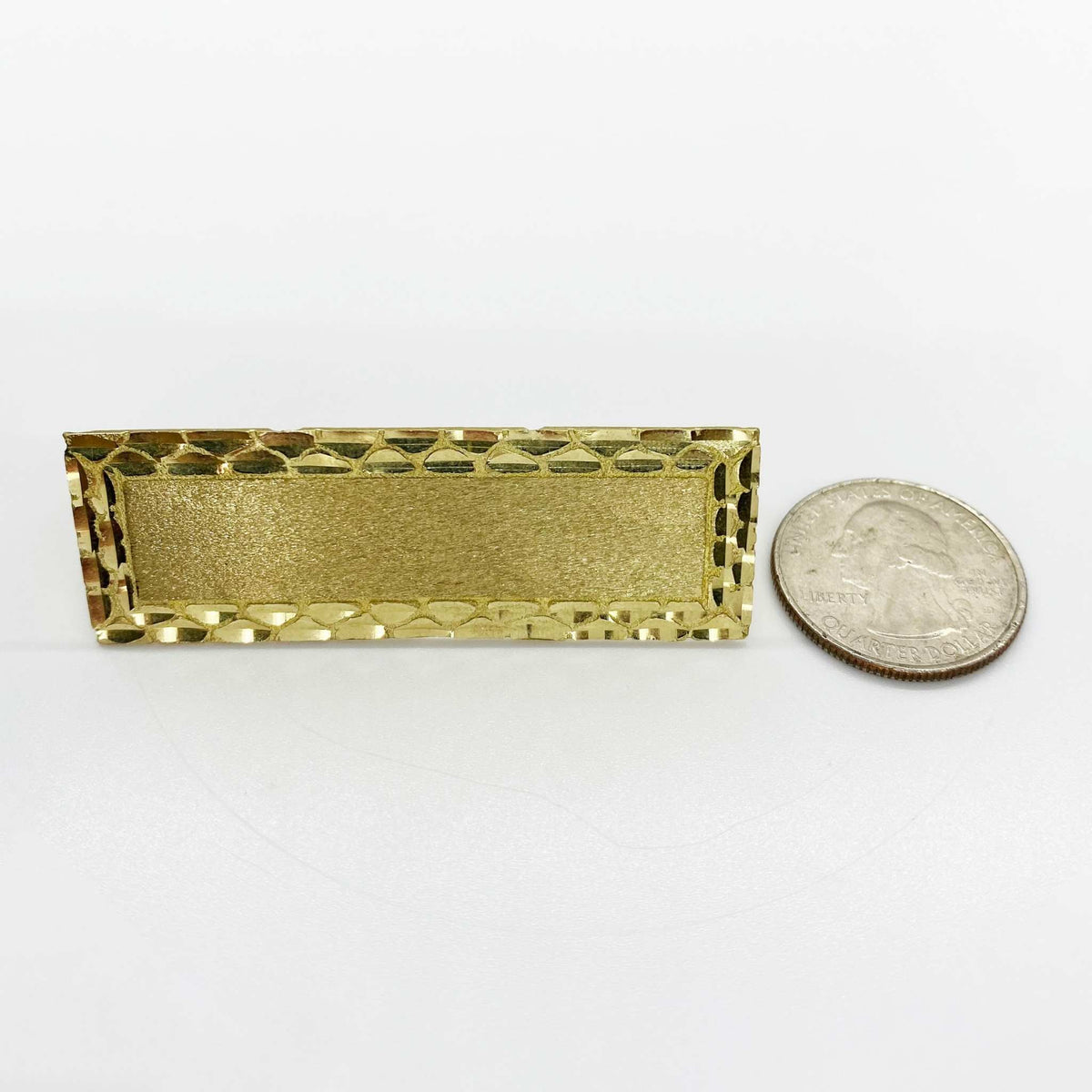 10k Gold rectangular three finger ring next to a silver dollar coin on a white background