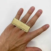 10k Gold rectangular three finger ring on a person's finger against a white background