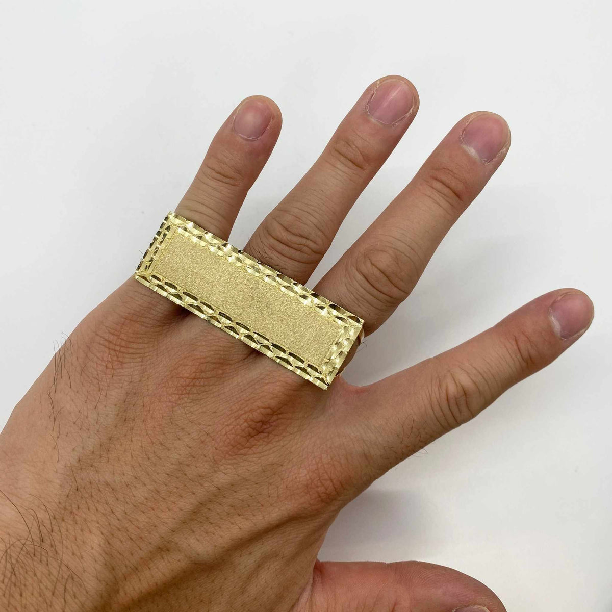 10k Gold rectangular three finger ring on a person's finger against a white background