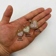 Open hand displaying small, medium, and large gold heart pendants with pink stones.