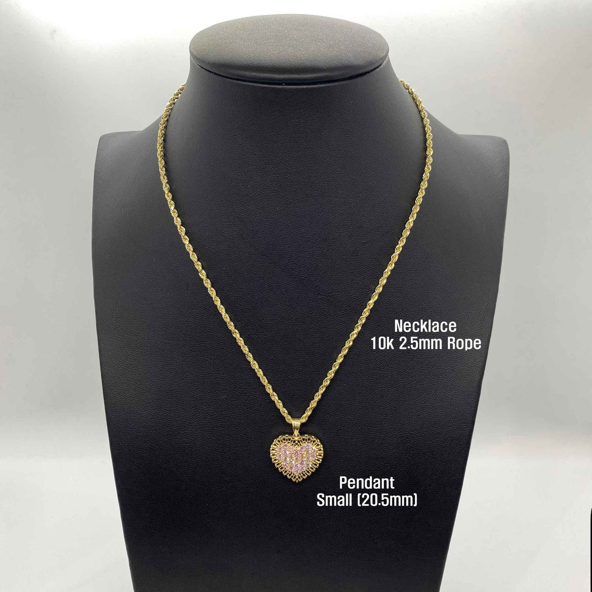 Open hand displaying small, medium, and large gold heart pendants with pink stones.