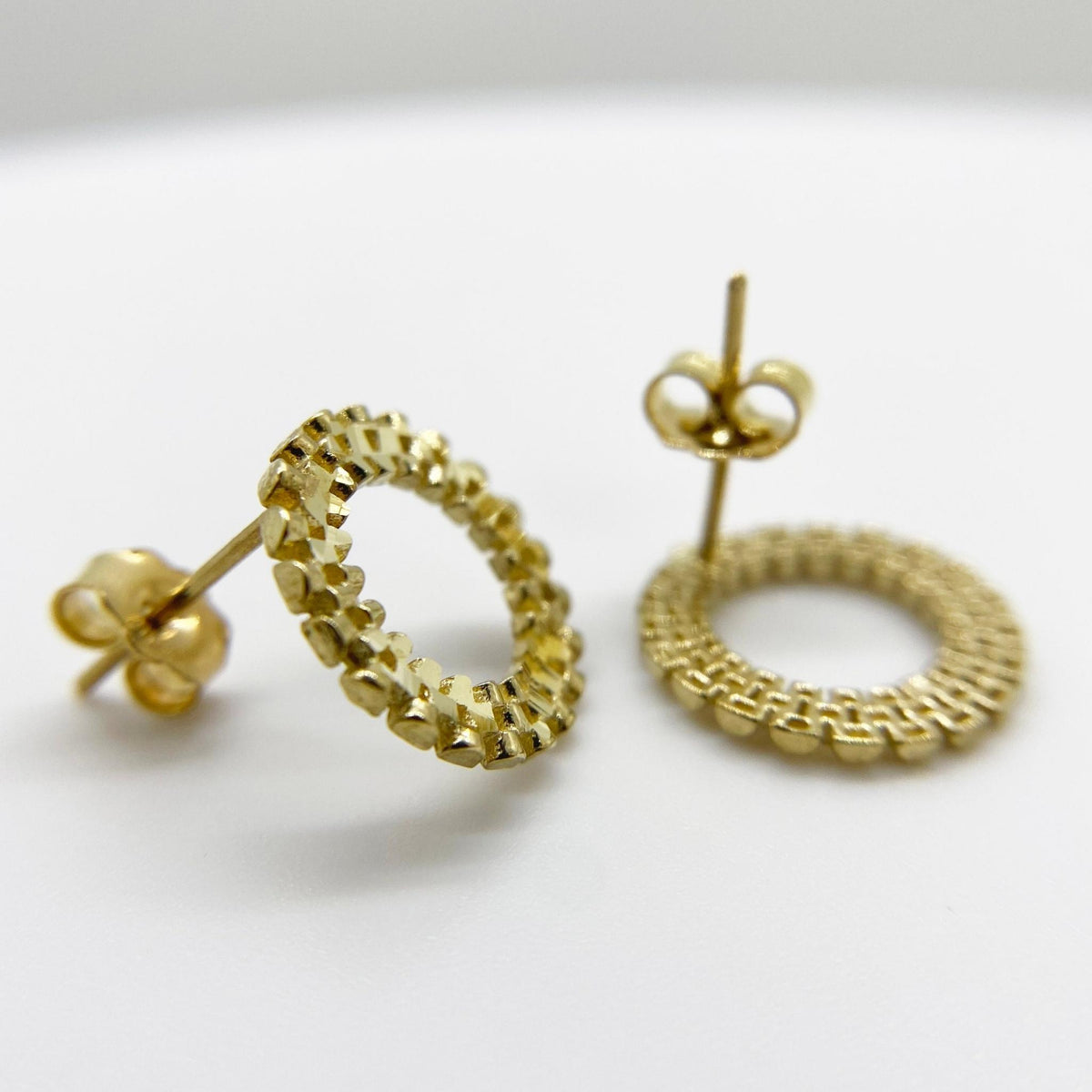 Pair of 10k yellow gold stud earrings featuring a textured, beaded, rollie-style circular design.