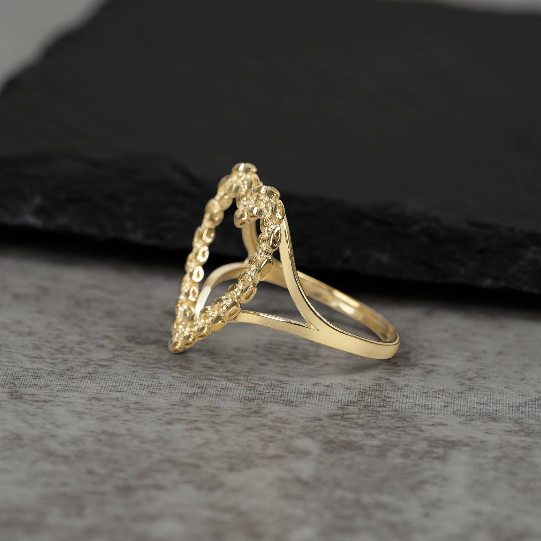 Side view of a 10k yellow gold ring showcasing a cut-out heart with link textures.