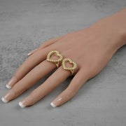 Two statement-making 10k gold openwork heart rings styled and worn together on a hand.