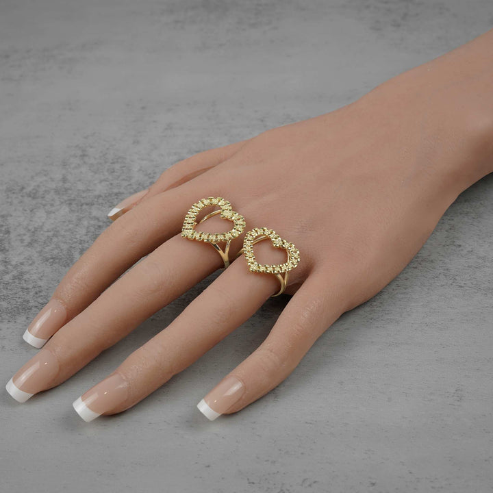 Two statement-making 10k gold openwork heart rings styled and worn together on a hand.