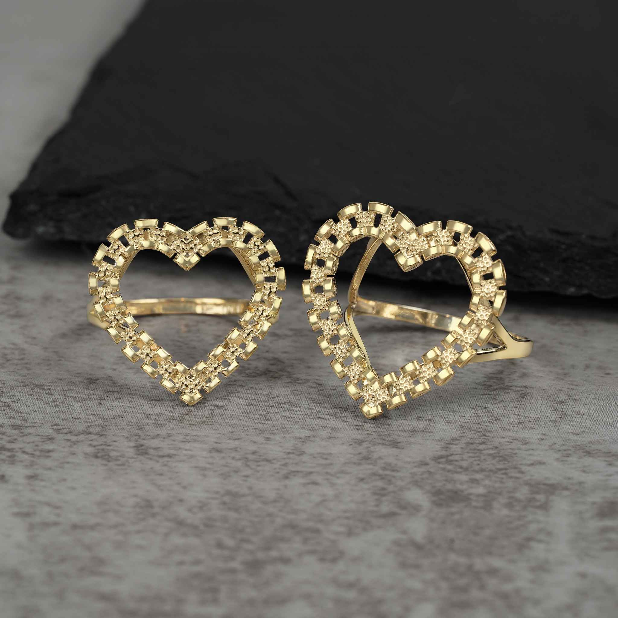 A pair of vintage-inspired 10k yellow gold heart rings featuring intricate link detailing.