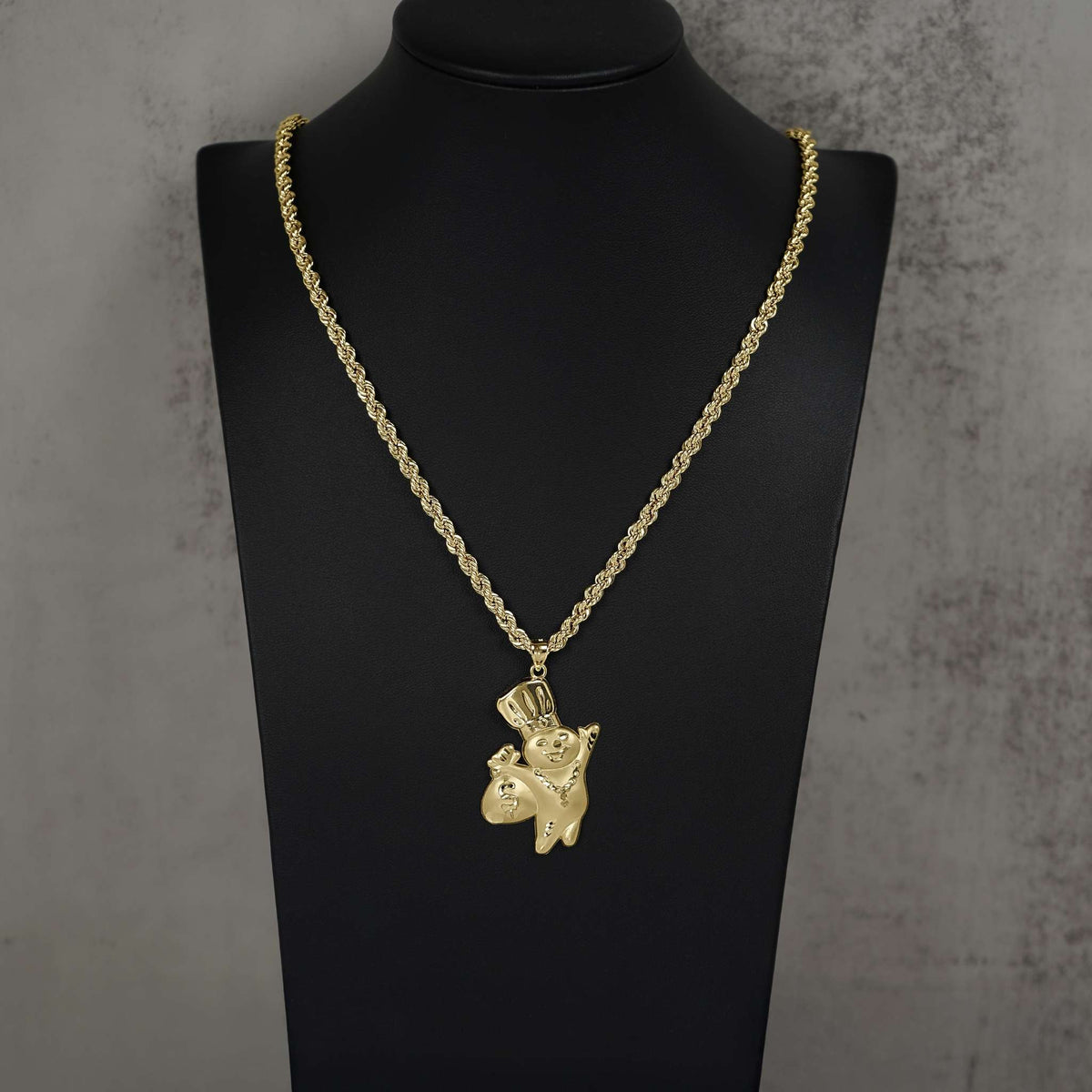 Polished 10k gold Pillsbury Doughboy pendant hanging on a rope chain, displayed on a bust.