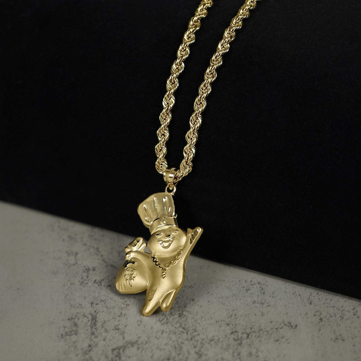 Polished 10k gold Pillsbury Doughboy pendant hanging on a rope chain, displayed on a bust.