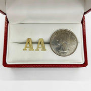 Pair of gold diamond-cut initial letter 'A' stud earrings displayed next to a quarter.