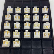 Full inventory display tray containing multiple pairs of gold diamond-cut initial letter stud earrings from A to Y.