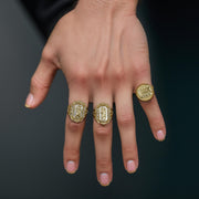 Model's hand wearing a round Last Supper ring alongside two ornate religious rings.
