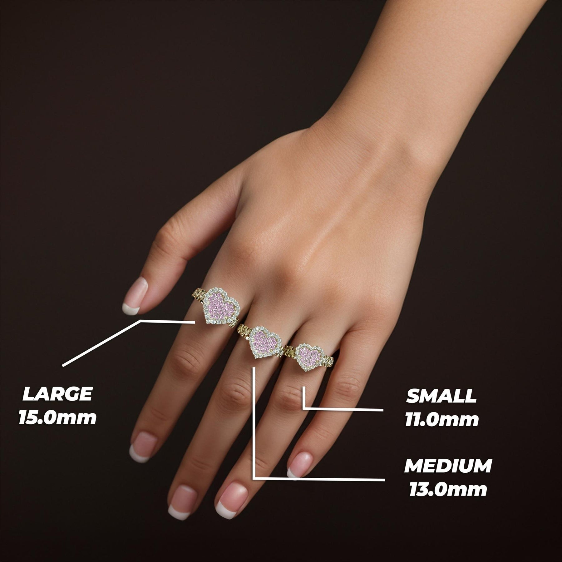 Size comparison of three gold pink cubic zirconia heart rings on a hand with measurements.