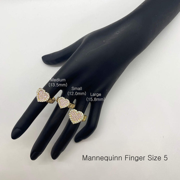 Three heart-shaped rings on a black mannequin hand with size labels.