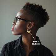 Profile view of a model wearing 20mm 10k gold teddy bear-shaped hoop earrings.