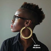 Side profile of a woman wearing 90mm 10k gold twisted round hoop earrings.