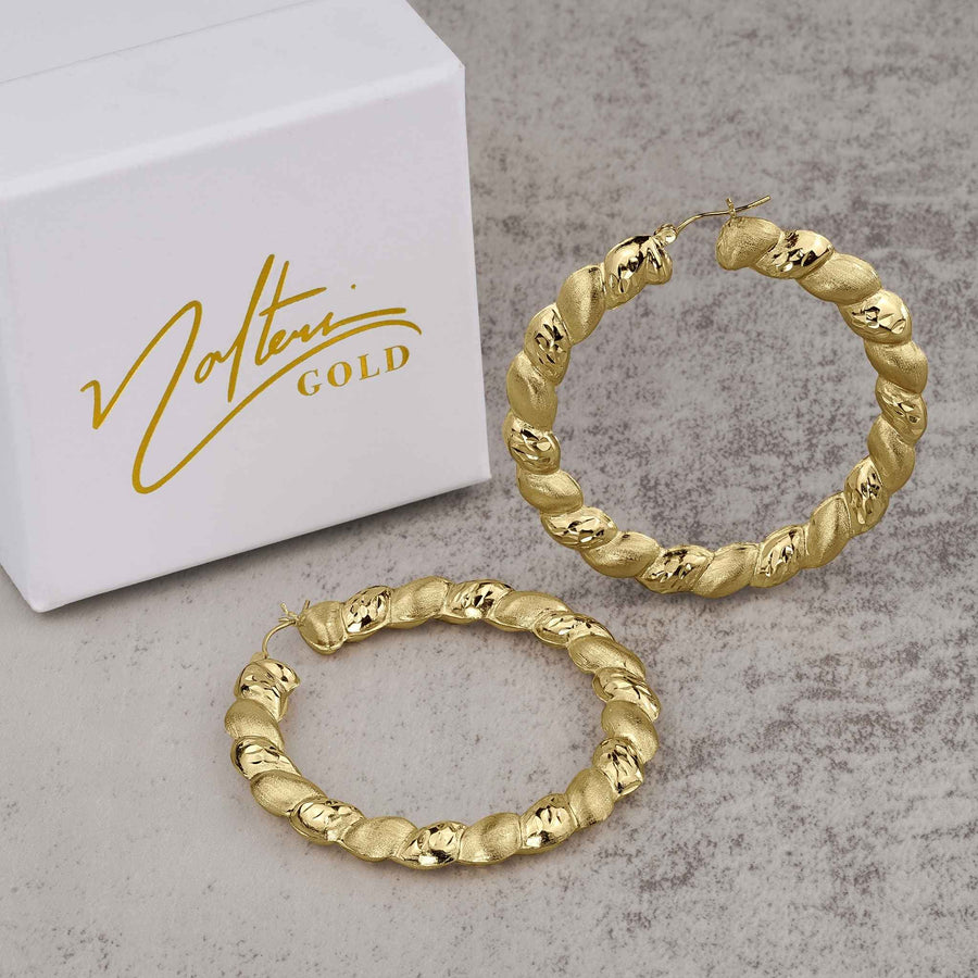 Pair of 10k yellow gold twisted round hoop earrings beside a Nolters Gold box.