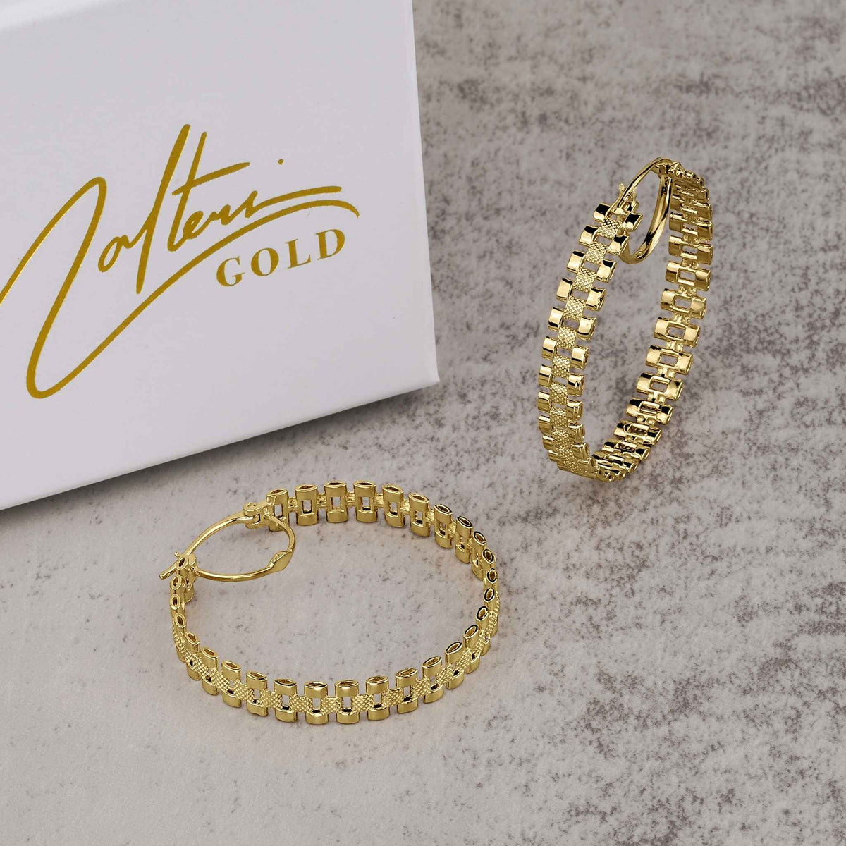 Pair of 10k gold rollie hoop earrings showcased with Nolters Gold packaging.