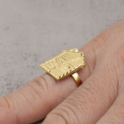 A 10k gold trap house signet ring being worn on a person's pinky finger.