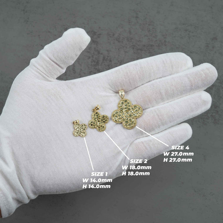 Three different sized gold nugget clover pendants shown on a white-gloved hand with measurement guides.