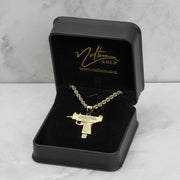 Gold Uzi pendant necklace on a chain inside a black presentation box.