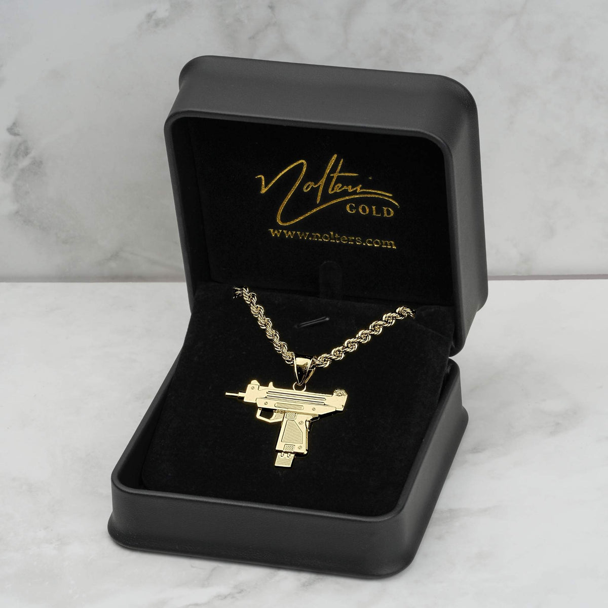 Gold Uzi pendant necklace on a chain inside a black presentation box.