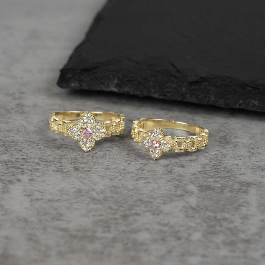 Two 10k Clover Rollie gold rings with Cubic Zirconia on a gray surface