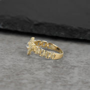 Side view of a 10K gold ring with cubic zirconia on a gray surface.
