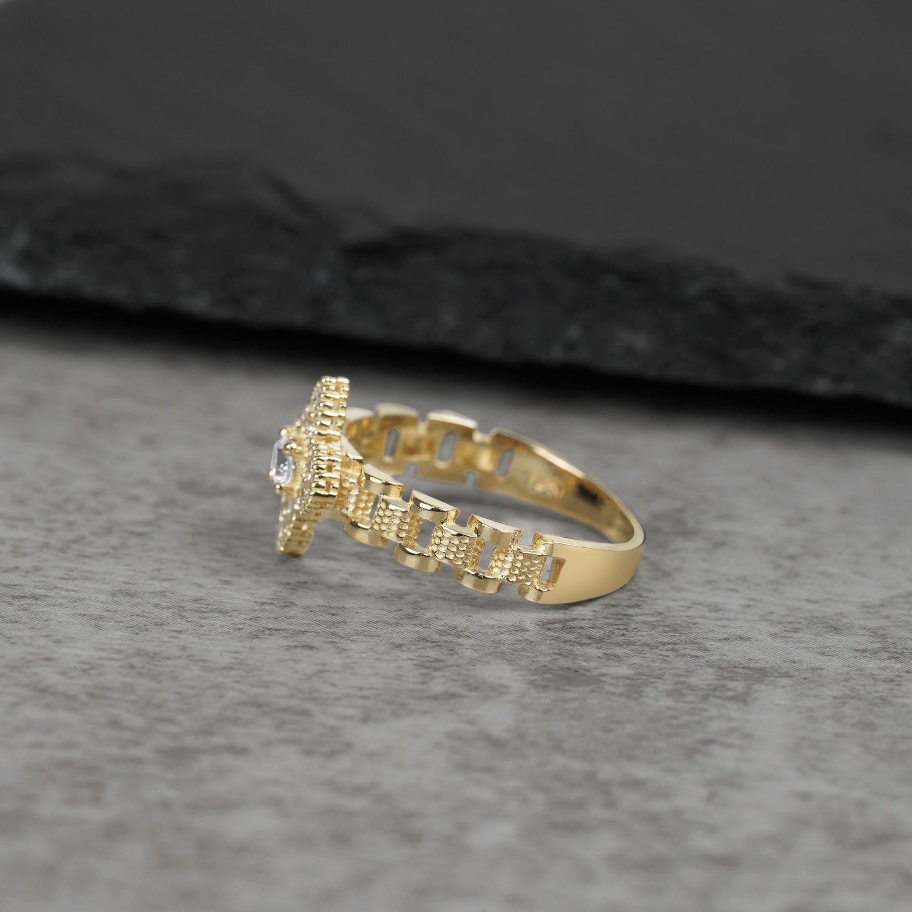 Side view of a 10K gold ring with cubic zirconia on a gray surface.
