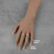Hand wearing two 10k rings with size labels on a gray background