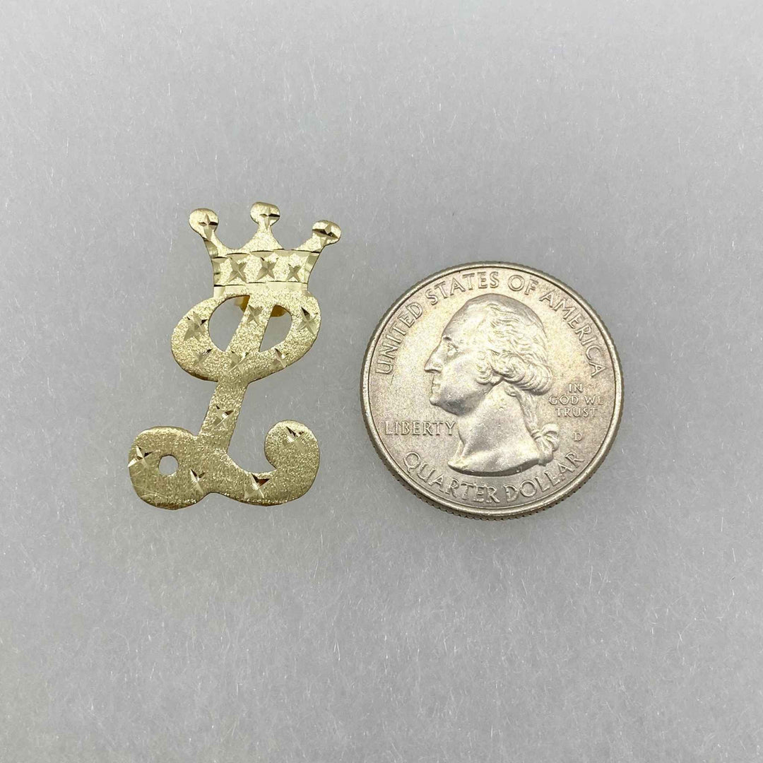 Gold crown-topped cursive letter "L" earring next to a quarter for size reference.