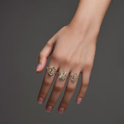 Hand wearing three 10k yellow gold vintage cursive initial rings on dark background.