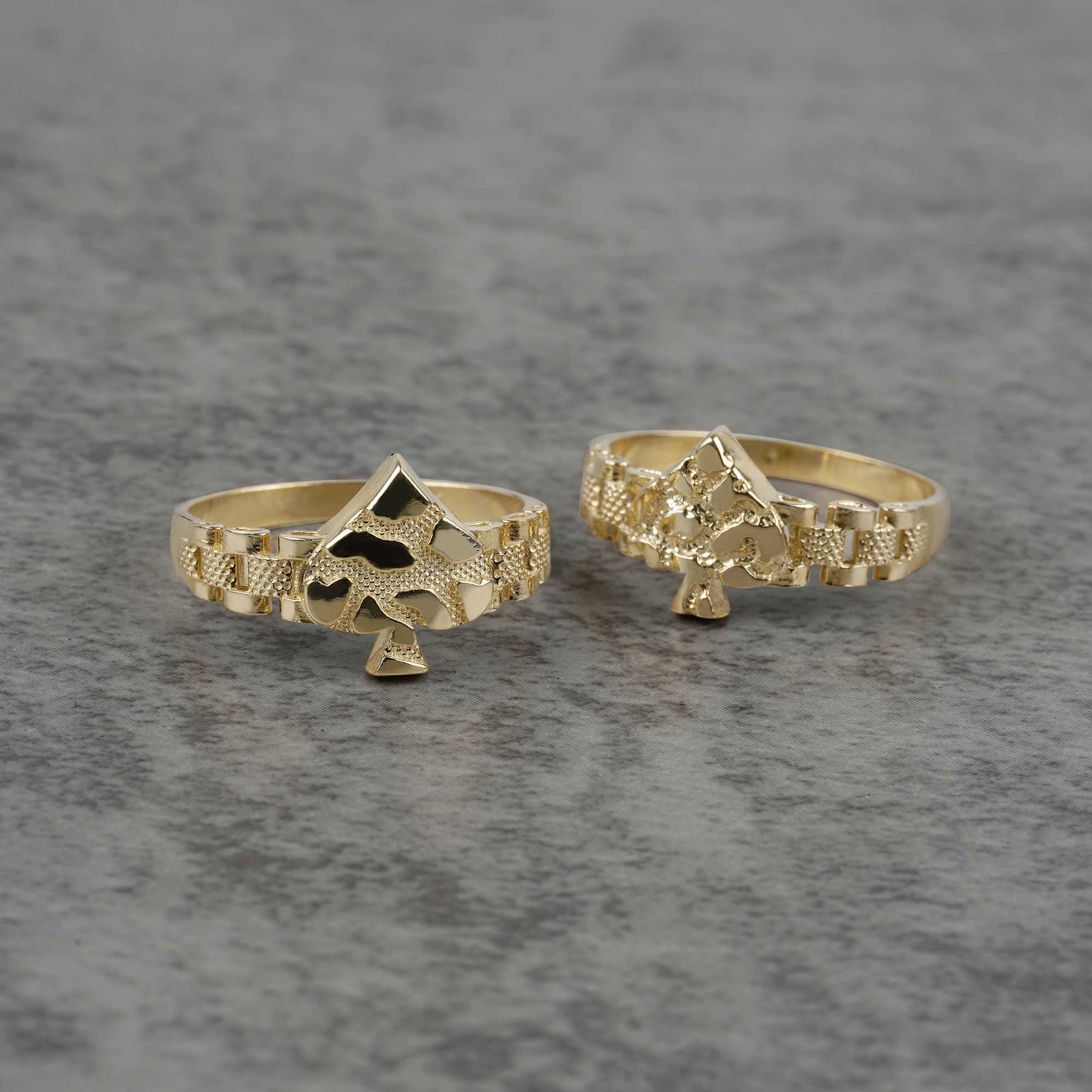front view of two 10K gold vintage spade nugget rings on a gray surface