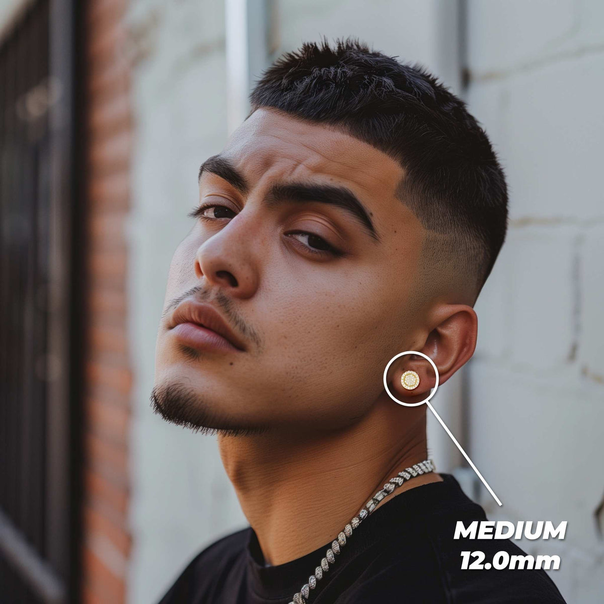 Man wearing a medium 12.0mm gold Vinx round cubic zirconia stud earring on his ear.