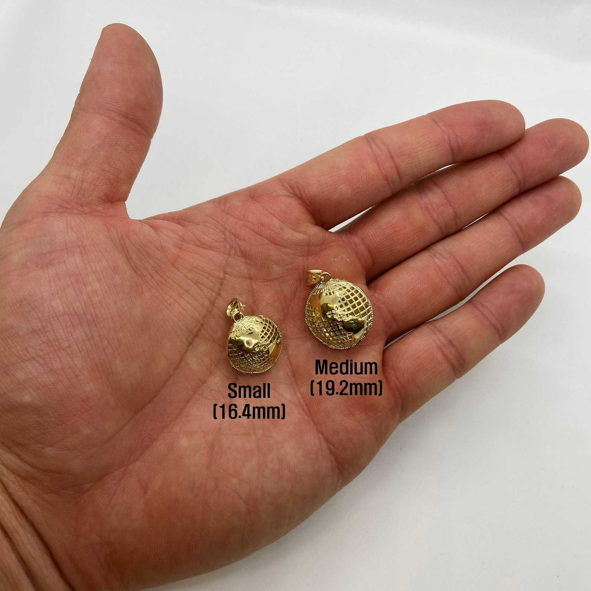 Small and Medium 10k gold 3D world globe pendants held in an open hand